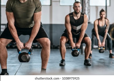 Group of people lifting weights at crossfit training at gym.