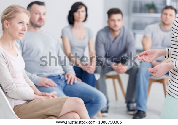 Group of people listening to a woman sharing\
her story of drug addiction and\
rehab