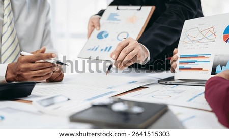 A group of people are looking at a table with a lot of papers and graphs. They are discussing the data and making decisions based on it