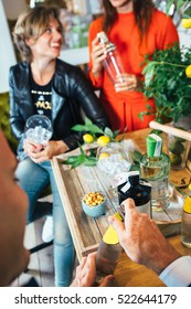 Group Of People Making Gin Tonic Cocktails And Having Fun Sitting At Table.