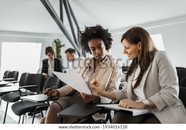 Group of people, making plans together, two\
females reading some\
documents.