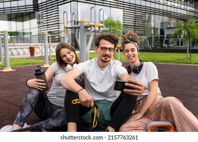 Group Of People Man And Women Male And Female Modern Friends Before Or After Training In Sitting In Open Gym Modern Outdoor Fitness Park Taking Selfie Photos With Mobile Phone Copy Space