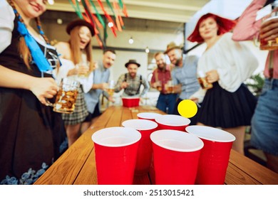 Group of people meeting at pub for beer festival celebration, having fun and playing beer pong. Concept of Oktoberfest, festival, party, brewery, traditions - Powered by Shutterstock