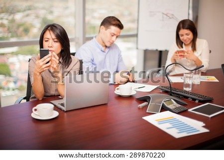 Group of people in a meeting room using their smartphones and ignoring work for a while