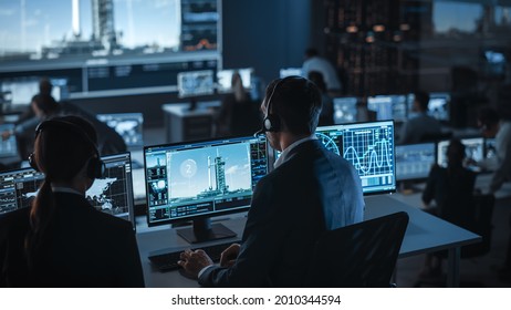 Group of People in Mission Control Center Witness Space Rocket Launch. Flight Control Employees Sit in Front Computer Displays and Monitor the Crewed Mission. - Powered by Shutterstock