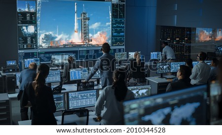 Group of People in Mission Control Center Witness Successful Space Rocket Launch. Flight Control Employees Sit in Front Computer Displays and Monitor the Crewed Mission. Excited and Tension Moment.