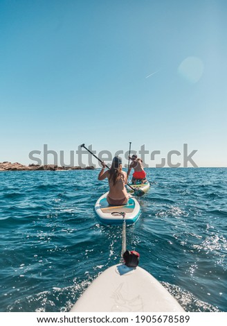 A group of people paddle with SUP stand up paddle boards on a hot day in the Adriatic sea in Montenegro