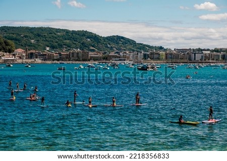 Group of people paddle surfing on La Concha beach in San Sebastian