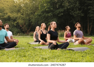Group of people practicing yoga on mats outdoors. Lotus pose - Powered by Shutterstock