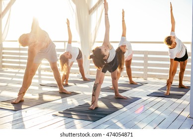 group of people practicing yoga on the seaside during the sunrise