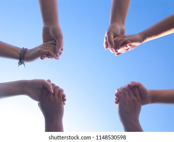 Group Of People Praying In A Circle Holding Hands As Their Hands Make The Shape Of The Cross