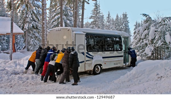 Group of people\
pushing a bus in the snow