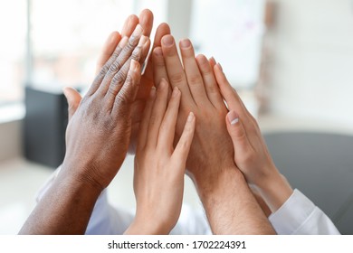 Group of people putting hands together indoors. Unity concept