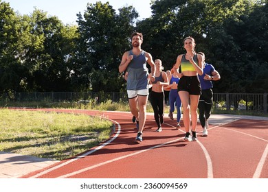 Group of people running at stadium on sunny day. Space for text - Powered by Shutterstock