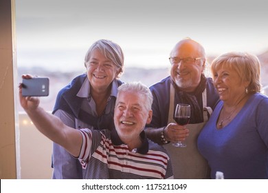 Group Of People Senior Adults Caucasian Having Fun Celebrating Together Outdoor At Home In The Terrace With Rooftop View. Taking Picture Selfie With Phone Technology Smiling And Laughing With Joy. 
