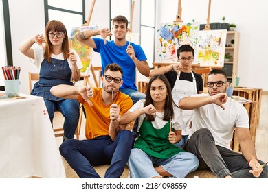 Group Of People Sitting At Art Studio With Angry Face, Negative Sign Showing Dislike With Thumbs Down, Rejection Concept 