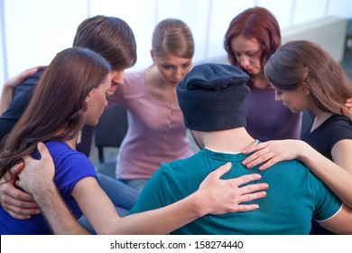 Group of people sitting in a circle. Hugging each other 
