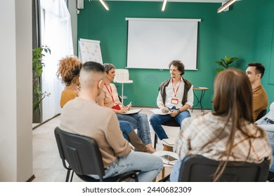 A group of people sitting in a circle with therapists man and a woman discussing and providing emotional support solving problem mental awareness and stigma self care concept - Powered by Shutterstock