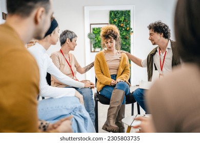 A group of people sitting in a circle with two therapists and a woman in the center discussing and providing emotional support for her The focus is on the woman but everyone is engaged in conversation - Powered by Shutterstock