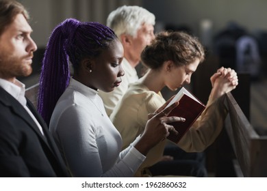 Group Of People Sitting On The Bench In Church And Praying During Ceremony