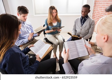 Group Of People Sitting On Chair In Circle Reading Bibles