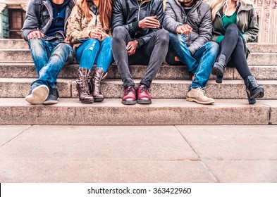 Group of people sitting on a staircase outdoors, close up on low section body - Multiracial friends talking and having fun on a meeting outdoors