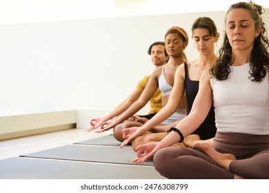 A group of people are sitting on yoga mats and meditating. Scene is peaceful and serene, as the people are meditating and focusing on their breathing. - Powered by Shutterstock