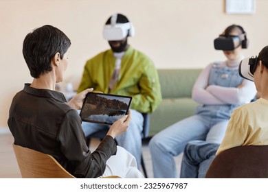 Group of people sitting in VR glasses and having virtual psychotherapy session with specialist - Powered by Shutterstock