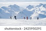 Group of people skiing and snowboarding down the ski slope or piste in Alps Mountains. Winter ski holidays 