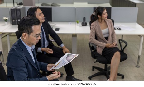 Group Of People In Smart Attire Is Listening To A Presentation In A Business Class Seminar. A Mixed Team Of Male And Female Office Workers Join A Discussion Session And Pay Attention In A Meeting