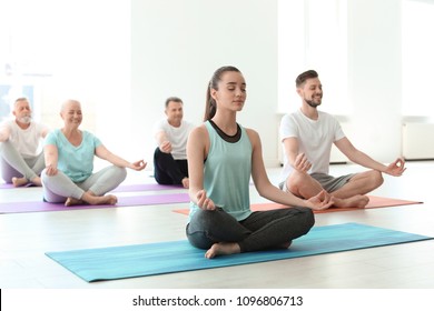 Group of people in sportswear practicing yoga indoors