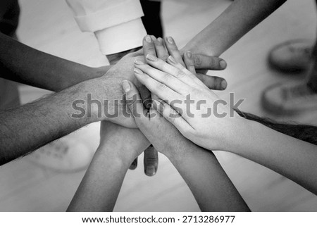 Group of people stacking their hands together, closeup. Black-and-white toning