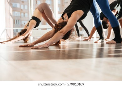 Group of people standing and doing yoga exercises barefoot in studio