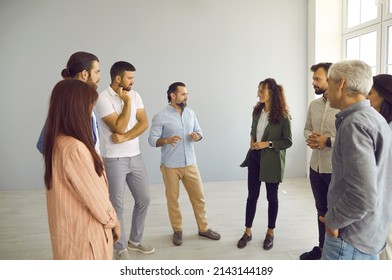 Group Of People Standing In Modern Office And Talking. Business Trainer Meeting With Team Of Men And Women, Having Interesting Discussion, Providing Expert Guidance And Helping Find Better Solution