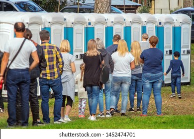 Group of people standing near portable toilets in a park