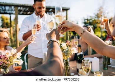 Group of people toasting drinks at a party. Young friends having drinks at garden restaurant. - Powered by Shutterstock