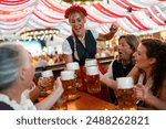 group of people in traditional Bavarian attire toasting with beer steins and enjoying a festive indoor event in an Oktoberfest tent with red and white drapes in the background