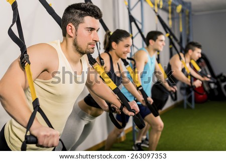 Group of people training at elastic rope in gym