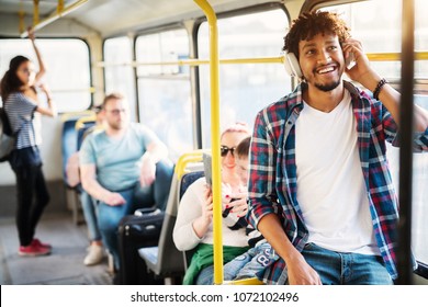 A group of people traveling by the bus with a young cheerful handsome man in the first plan of the picture who is listening to music on his headphones and smiling. - Powered by Shutterstock