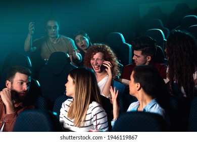 Group of people trying to watch movie in cinema while young woman talking at phone. - Powered by Shutterstock