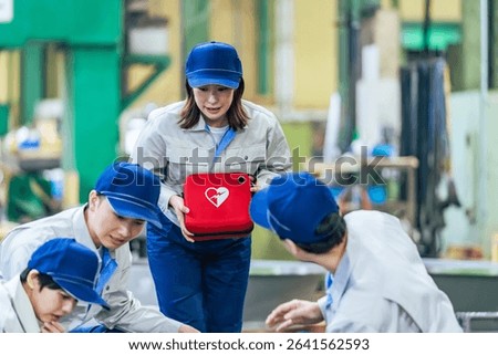 A group of people using an AED to help a worker who collapsed at a factory