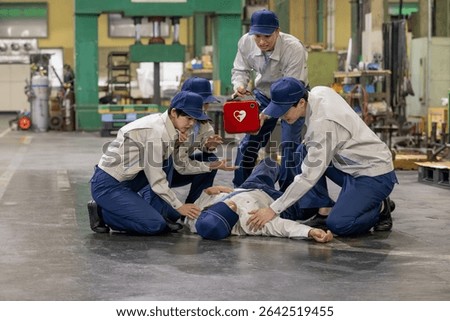 A group of people using an AED to help a worker who collapsed at a factory
