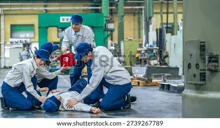 A group of people using an AED to help a worker who collapsed at a factory
