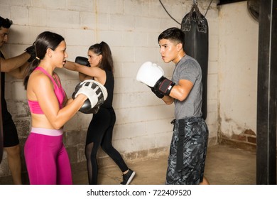 Group Of People Using Boxing Mitts To Train With A Partner During A Boxing Class In A Gym