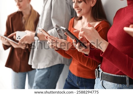Group of people using different gadgets near light wall indoors, closeup. Modern technology