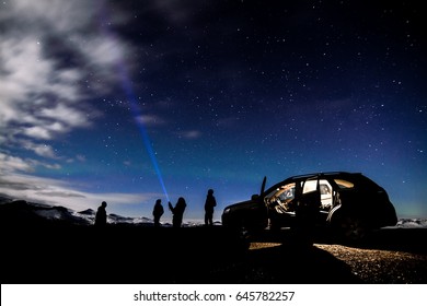 A Group Of People Using Flashlight Searching For Stars On The Beautiful Night In Iceland  With Aurora Light Shining On The Sky 