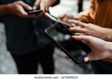 Group of people using and looking at mobile phone white standing together. Close up of people hand playing smartphone.