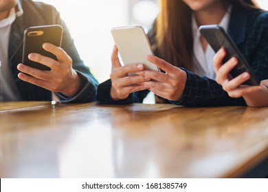 Group Of People Using And Looking At Mobile Phone While Sitting Together