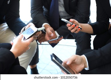 Group Of People Using Smart Phones Sitting At The Meeting, Close Up On Hands.