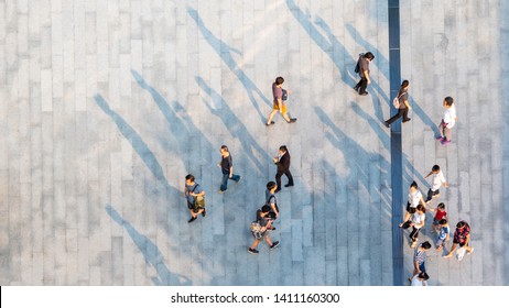 Group Of People Walk On Across The Pedestrian Concrete Landscape In The City Street (Aerial Top View)